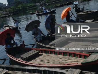 Boatmen hold umbrellas under the hot sun as they wait for passengers at the old Buriganga River channel in Dhaka, Bangladesh, on September 1...