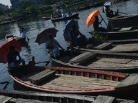 Boatmen hold umbrellas under the hot sun as they wait for passengers at the old Buriganga River channel in Dhaka, Bangladesh, on September 1...