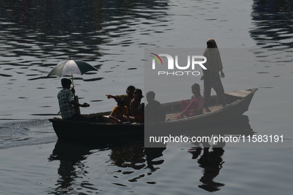 Children ride in a boat as it moves through the pitch-black water of the old Buriganga River channel in Dhaka, Bangladesh, on September 17,...