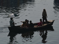 Children ride in a boat as it moves through the pitch-black water of the old Buriganga River channel in Dhaka, Bangladesh, on September 17,...