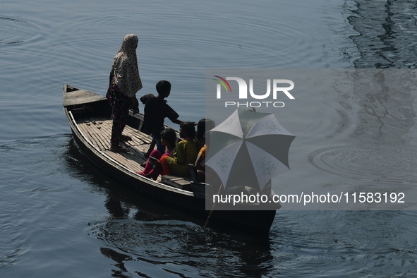 Children ride in a boat as it moves through the pitch-black water of the old Buriganga River channel in Dhaka, Bangladesh, on September 17,...