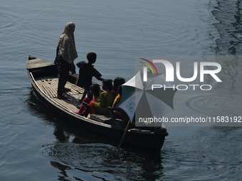 Children ride in a boat as it moves through the pitch-black water of the old Buriganga River channel in Dhaka, Bangladesh, on September 17,...