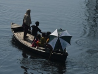 Children ride in a boat as it moves through the pitch-black water of the old Buriganga River channel in Dhaka, Bangladesh, on September 17,...