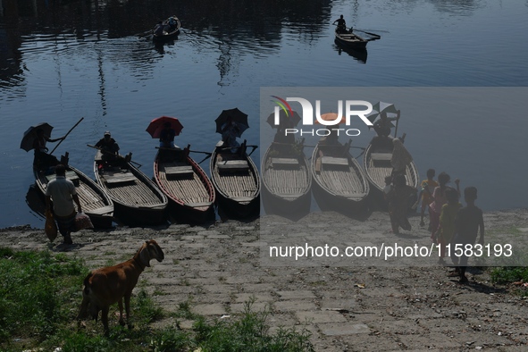 Boatmen hold umbrellas under the hot sun as they wait for passengers at the old Buriganga River channel in Dhaka, Bangladesh, on September 1...