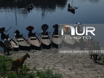 Boatmen hold umbrellas under the hot sun as they wait for passengers at the old Buriganga River channel in Dhaka, Bangladesh, on September 1...