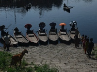 Boatmen hold umbrellas under the hot sun as they wait for passengers at the old Buriganga River channel in Dhaka, Bangladesh, on September 1...