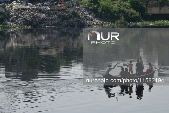 Children ride in a boat as it moves through the pitch-black water of the old Buriganga River channel in Dhaka, Bangladesh, on September 17,...