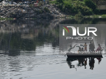 Children ride in a boat as it moves through the pitch-black water of the old Buriganga River channel in Dhaka, Bangladesh, on September 17,...