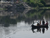 Children ride in a boat as it moves through the pitch-black water of the old Buriganga River channel in Dhaka, Bangladesh, on September 17,...