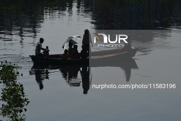 Children ride in a boat as it moves through the pitch-black water of the old Buriganga River channel in Dhaka, Bangladesh, on September 17,...