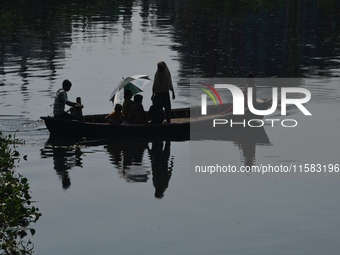 Children ride in a boat as it moves through the pitch-black water of the old Buriganga River channel in Dhaka, Bangladesh, on September 17,...