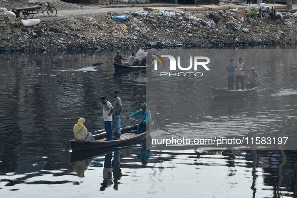 Local passengers cross the old Buriganga River channel by boat as it moves through pitch-black water in Dhaka, Bangladesh, on September 17,...