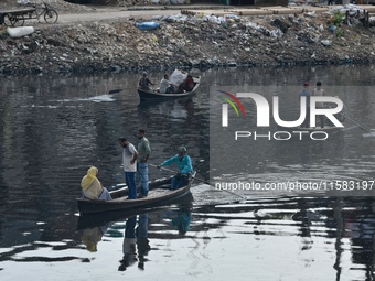 Local passengers cross the old Buriganga River channel by boat as it moves through pitch-black water in Dhaka, Bangladesh, on September 17,...