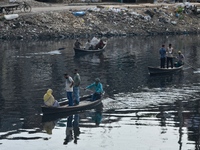 Local passengers cross the old Buriganga River channel by boat as it moves through pitch-black water in Dhaka, Bangladesh, on September 17,...