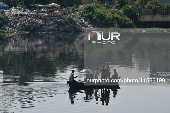 Children ride in a boat as it moves through the pitch-black water of the old Buriganga River channel in Dhaka, Bangladesh, on September 17,...