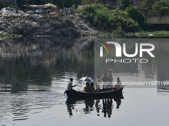 Children ride in a boat as it moves through the pitch-black water of the old Buriganga River channel in Dhaka, Bangladesh, on September 17,...