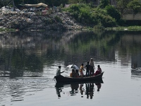 Children ride in a boat as it moves through the pitch-black water of the old Buriganga River channel in Dhaka, Bangladesh, on September 17,...