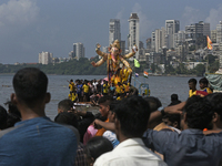 Devotees carry an idol of the elephant-headed god Lord Ganesha during an immersion procession to the Arabian Sea in Mumbai, India, on Septem...