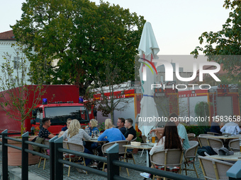 People dining at a restaurant with fire trucks parked nearby are seen in Frankfurt (Oder) on 17 September, 2024. After warnings of increasin...