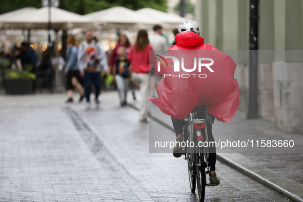 A cyclist wearing a raincoat is seen on the street in Krakow, Poland, on August 21, 2024. 