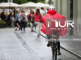 A cyclist wearing a raincoat is seen on the street in Krakow, Poland, on August 21, 2024. (