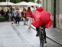 A cyclist wearing a raincoat is seen on the street in Krakow, Poland, on August 21, 2024. (