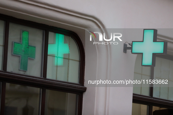 A glowing cross sign on a pharmacy is seen on the street in Krakow, Poland, on August 21, 2024. 