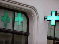 A glowing cross sign on a pharmacy is seen on the street in Krakow, Poland, on August 21, 2024. (