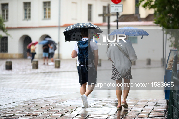 People with umbrellas walk in the rain on the street in Krakow, Poland, on August 21, 2024. 