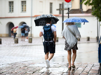 People with umbrellas walk in the rain on the street in Krakow, Poland, on August 21, 2024. (