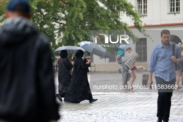 People with umbrellas walk in the rain on the street in Krakow, Poland, on August 21, 2024. 