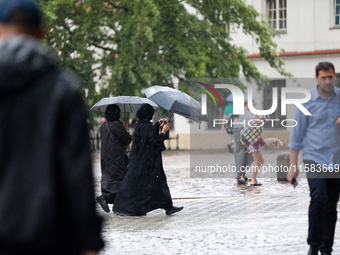 People with umbrellas walk in the rain on the street in Krakow, Poland, on August 21, 2024. (