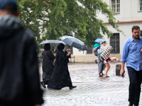 People with umbrellas walk in the rain on the street in Krakow, Poland, on August 21, 2024. (