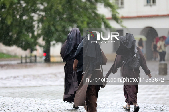 Nuns walk in the rain on the street in Krakow, Poland, on August 21, 2024. 