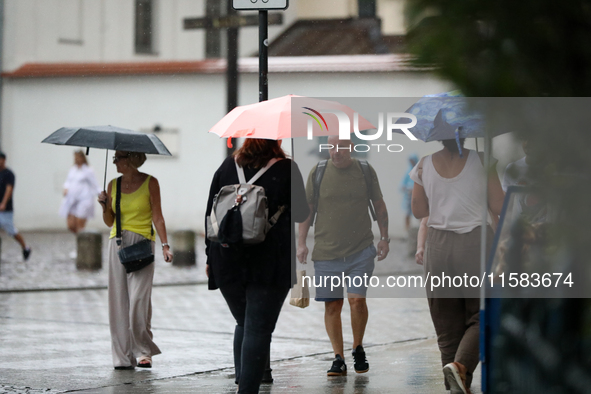 People with umbrellas walk in the rain on the street in Krakow, Poland, on August 21, 2024. 