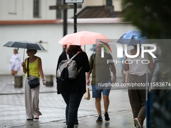 People with umbrellas walk in the rain on the street in Krakow, Poland, on August 21, 2024. (