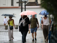 People with umbrellas walk in the rain on the street in Krakow, Poland, on August 21, 2024. (