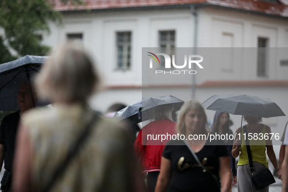 People with umbrellas walk in the rain on the street in Krakow, Poland, on August 21, 2024. 