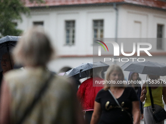 People with umbrellas walk in the rain on the street in Krakow, Poland, on August 21, 2024. (