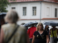 People with umbrellas walk in the rain on the street in Krakow, Poland, on August 21, 2024. (