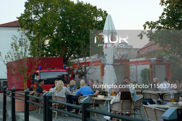 People dining at a restaurant with fire trucks parked nearby are seen in Frankfurt (Oder) on 17 September, 2024. After warnings of increasin...