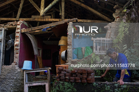 A man stands at his collapsed house after a 5.0 magnitude earthquake strikes in Kertasari, West Java, on September 18, 2024. At least 700 ho...