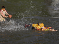 Hindu devotees immerse the idol of Vishwakarma, the god of machines and metallurgy, in the Bagmati River on the outskirts of Kathmandu, Nepa...