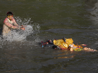 Hindu devotees immerse the idol of Vishwakarma, the god of machines and metallurgy, in the Bagmati River on the outskirts of Kathmandu, Nepa...