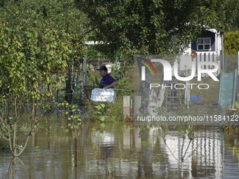 A man carries a pet transporter as he looks for stray cats in submerged social gardens on the outskirts of Wroclaw, Poland, on September 18,...