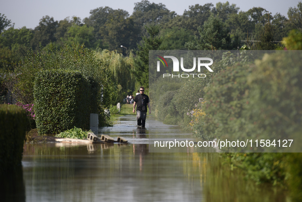 A man walks through floodwaters in the social gardens on the outskirts of Wroclaw, Poland, on September 18, 2024. The government outlines a...