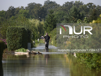 A man walks through floodwaters in the social gardens on the outskirts of Wroclaw, Poland, on September 18, 2024. The government outlines a...