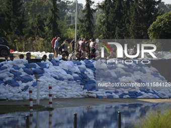 People and members of the territorial defense army fill bags with sand as they prepare for the flood wave to reach the southwestern city of...