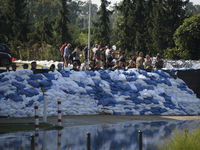 People and members of the territorial defense army fill bags with sand as they prepare for the flood wave to reach the southwestern city of...