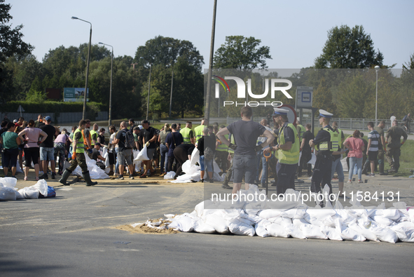 People and members of the territorial defense army fill bags with sand as they prepare for the flood wave to reach the southwestern city of...